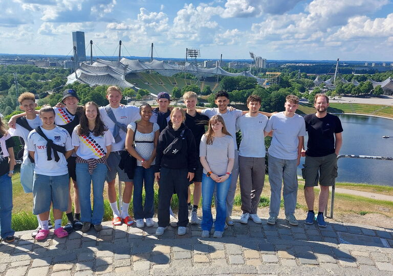 Gruppenfoto der Klasse Q1d mit Herrn Neumann mit dem Olympiastadion in München im Hintergrund