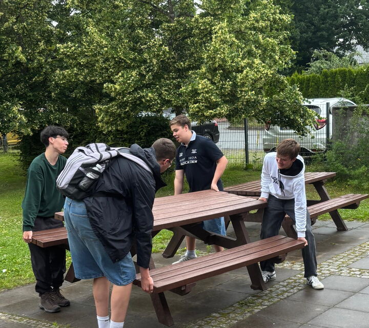 Vier Schüler tragen einen Picknicktisch