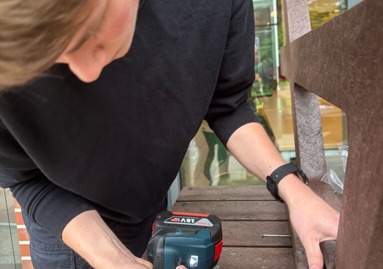 Ein Schüler verschraubt einen Picknicktisch