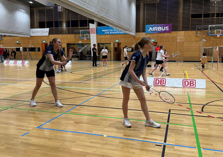 Zwei Spielerinnen spielen Badminton im dunkelblauen Trikot.