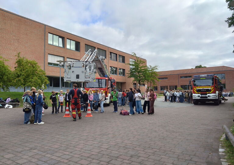 Bild mit zwei Feuerwehrautos und zahlreichen Schülern darum