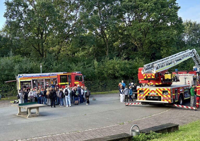 Schüler stehen vor den Feuerwehrfahrzeugen