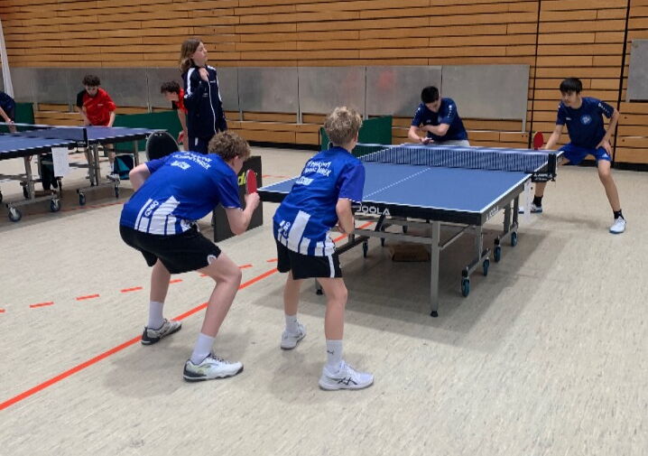 Vier Spieler spielen Tischtennis an einer Tischtennisplatte