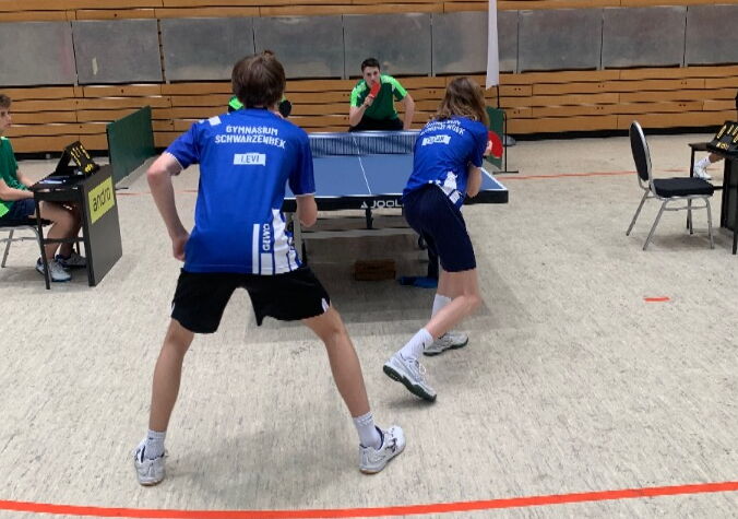 Foto von vier Tischtennisspielern, die gerade eine Partie spielen