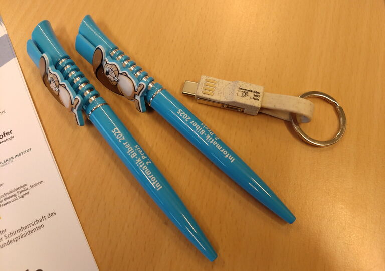 zwei blaue Kugelschreiber und ein USB-Kabel als Preise