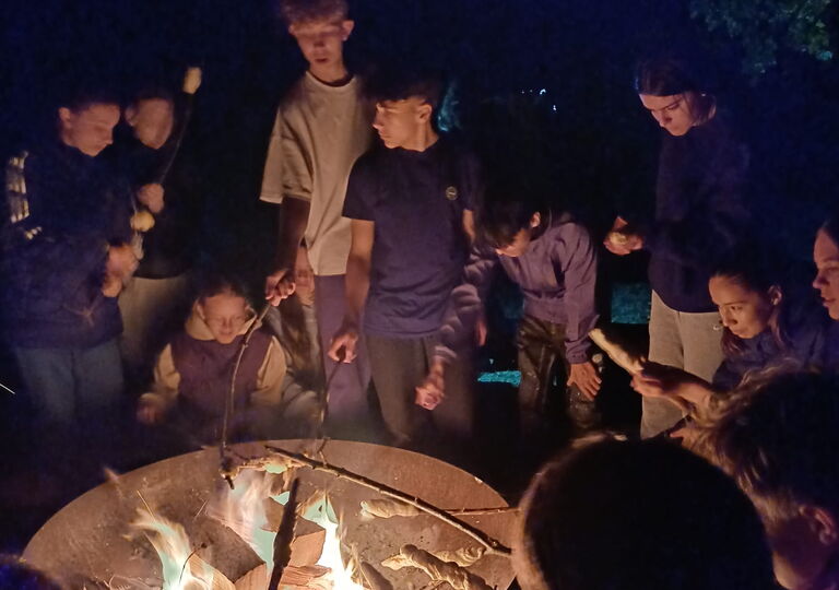 Schüler mit Stockbrot über einer Feuerschale