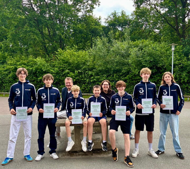 Sieben Schüler der U18-Tischtennis-Mannschaft präsentieren ihre Urkunden, die sie von Bürgermeister Norbert Lütjens und Schulleiterin Kristin Krause erhalten haben.