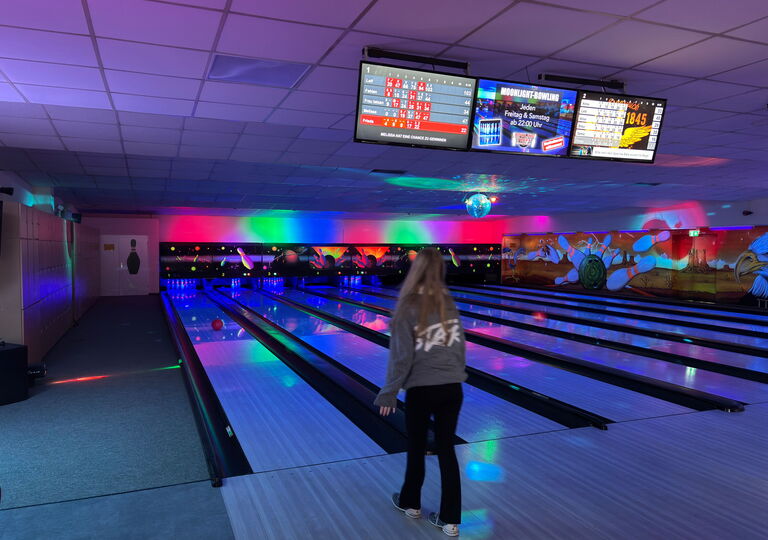 Bild eines Mädchens, das gerade eine Bowlingkugel geworfen hat