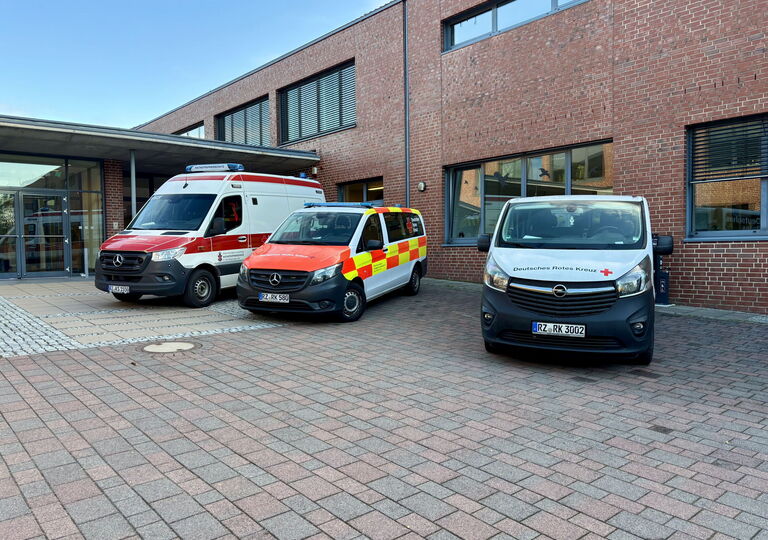 drei Fahrzeuge des Deutschen Roten Kreuzes vor dem Schulgebäude