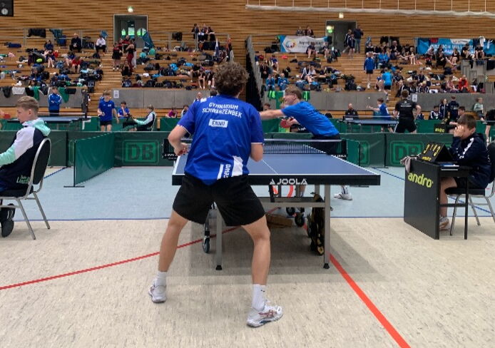 Ein Schüler in einem blauen Trikot des Gymnasiums spielt Tischtennis.