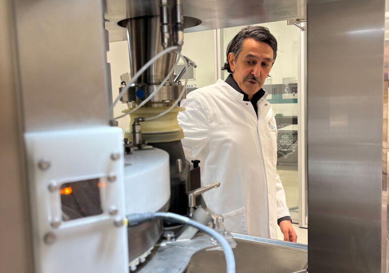 Ein Mitarbeiter im weißen Kittel erklärt eine Maschine