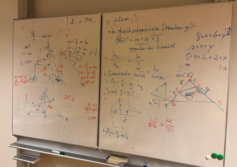 Vollgeschriebene Schultafel mit Matheformeln und Dreiecken