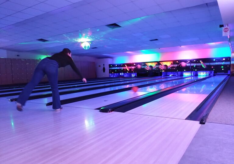 Schülerin wirft eine rote Bowlingkugel