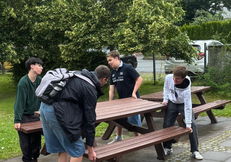 Vier Schüler tragen einen Picknicktisch