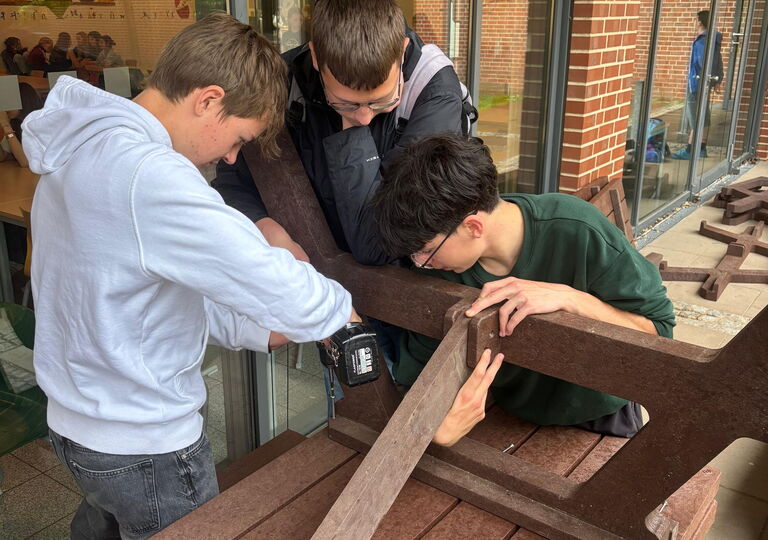 Drei Schüler bauen einen Picknicktisch zusammen