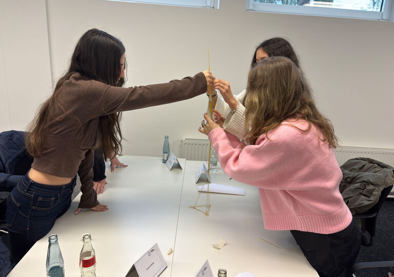 Drei Schülerinnen bauen einen Turm aus Holz