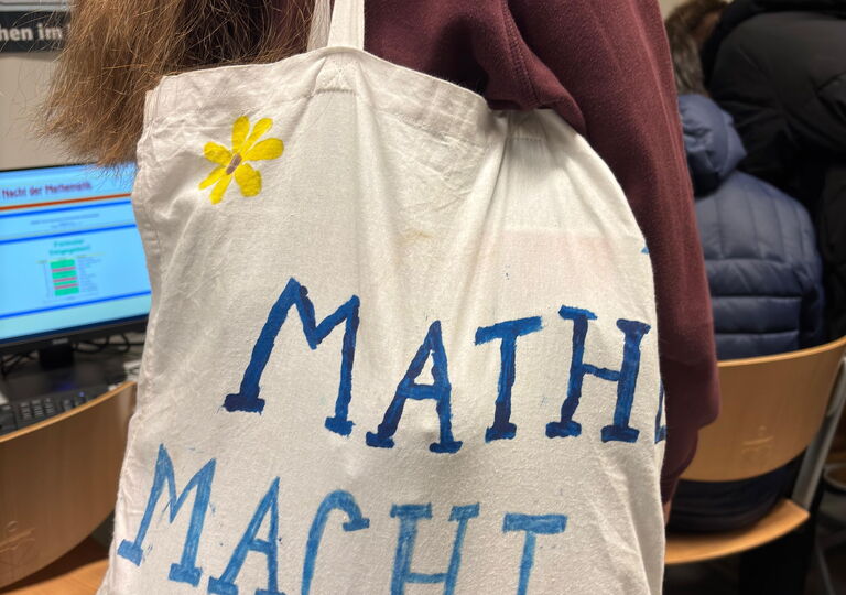 Schülerin mit Beutel, auf dem steht: "Mathe macht glücklich"