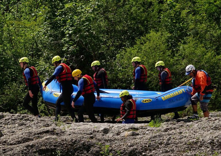 Acht Personen tragen ein blaues Schlauchboot