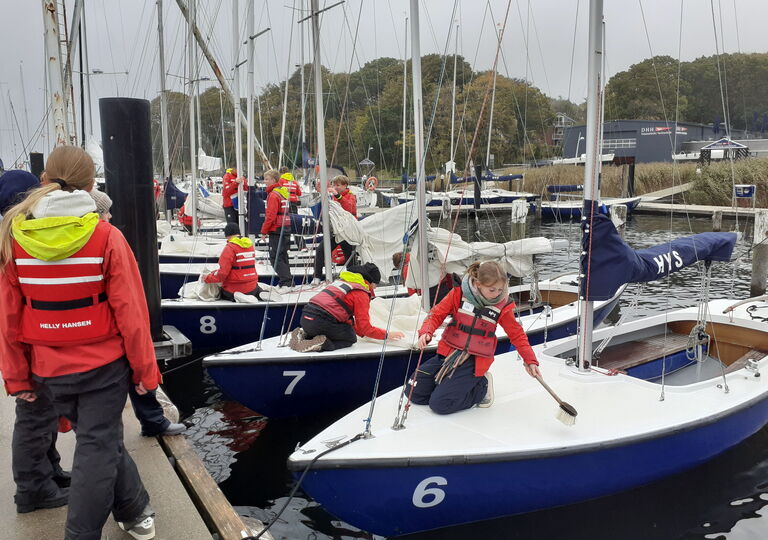Schüler putzen die Segelboote