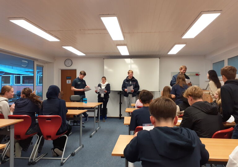 Schüler sitzen in einem Klassenraum und erhalten Urkunden