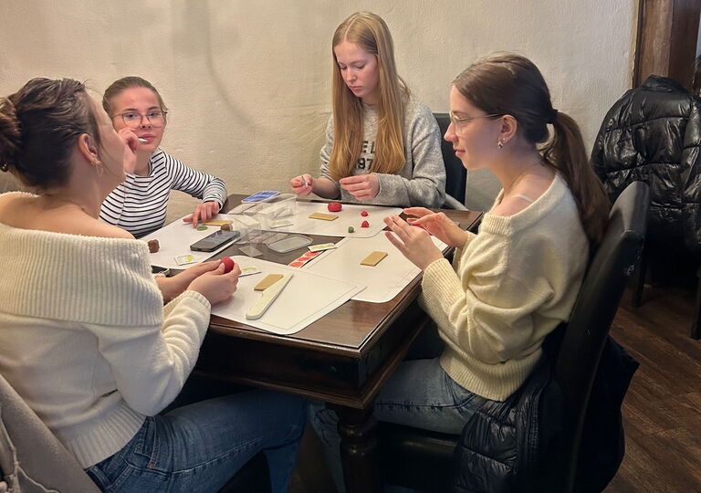 Vier Mädchen sitzen an einem Tisch und spielen ein Spiel