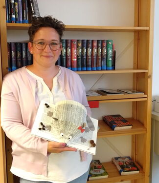 Frau Mücke Frau Mücke hält ein Igelbuch in der Hand