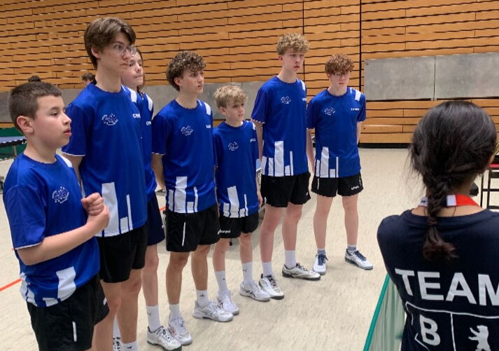 Tischtennismannschaft aus sieben Spielern in blauen Trikots