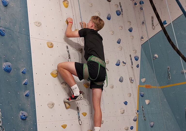 Ein Schüler klettert eine Kletterwand hinauf