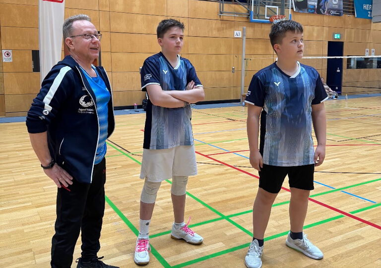 Zwei Spieler und der Trainer beobachten ein Spiel
