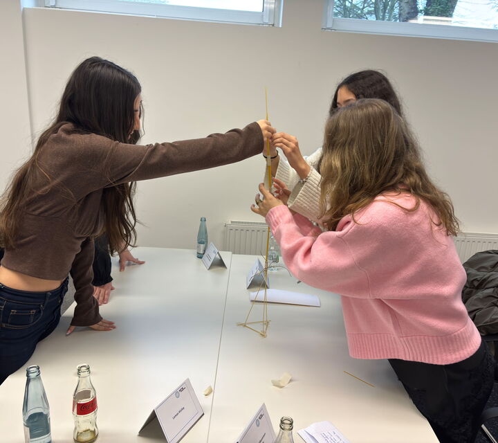 Drei Schülerinnen bauen einen Turm aus Holz