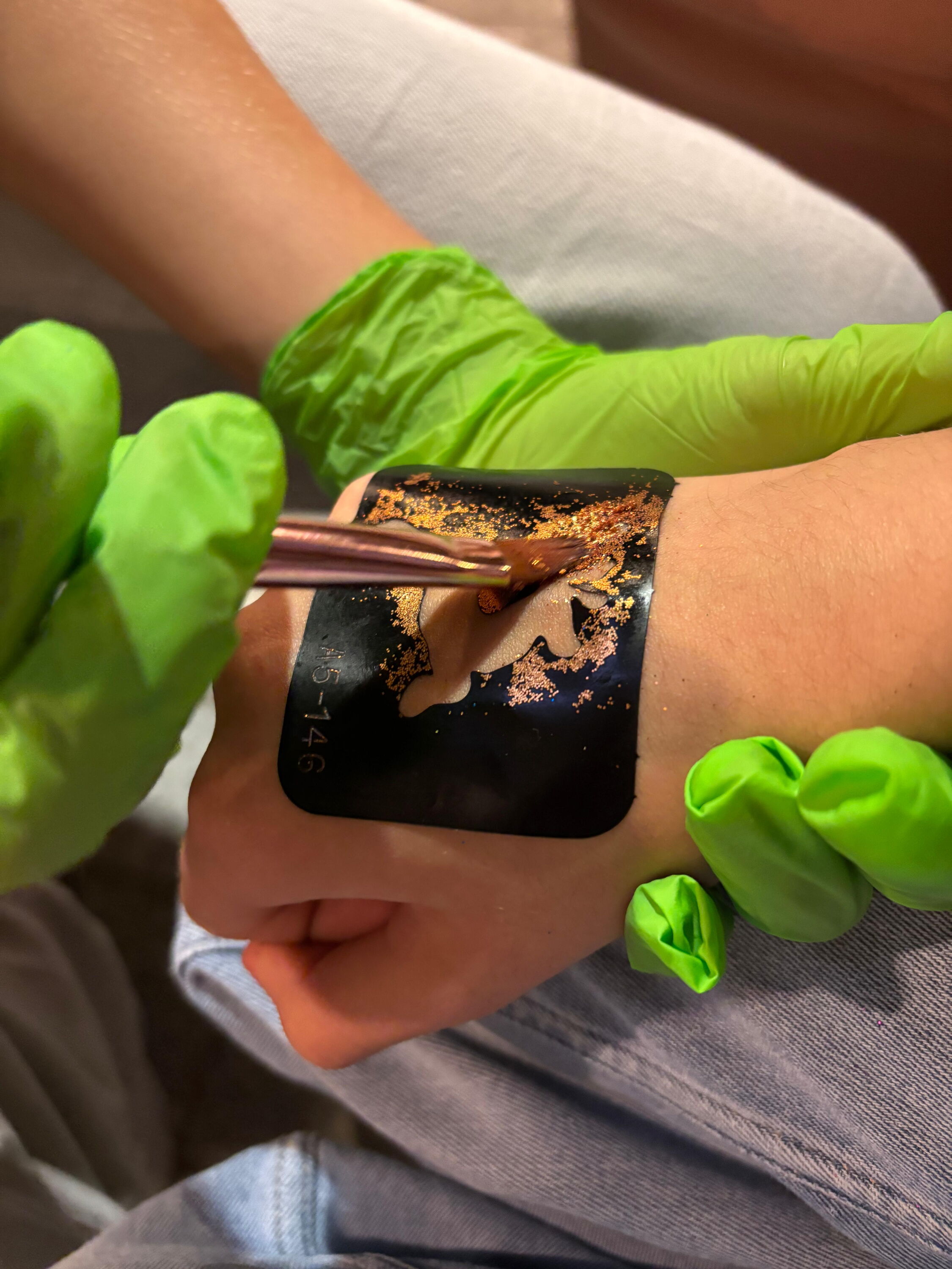 Ein Glitzertattoo wird auf eine Hand gemalt