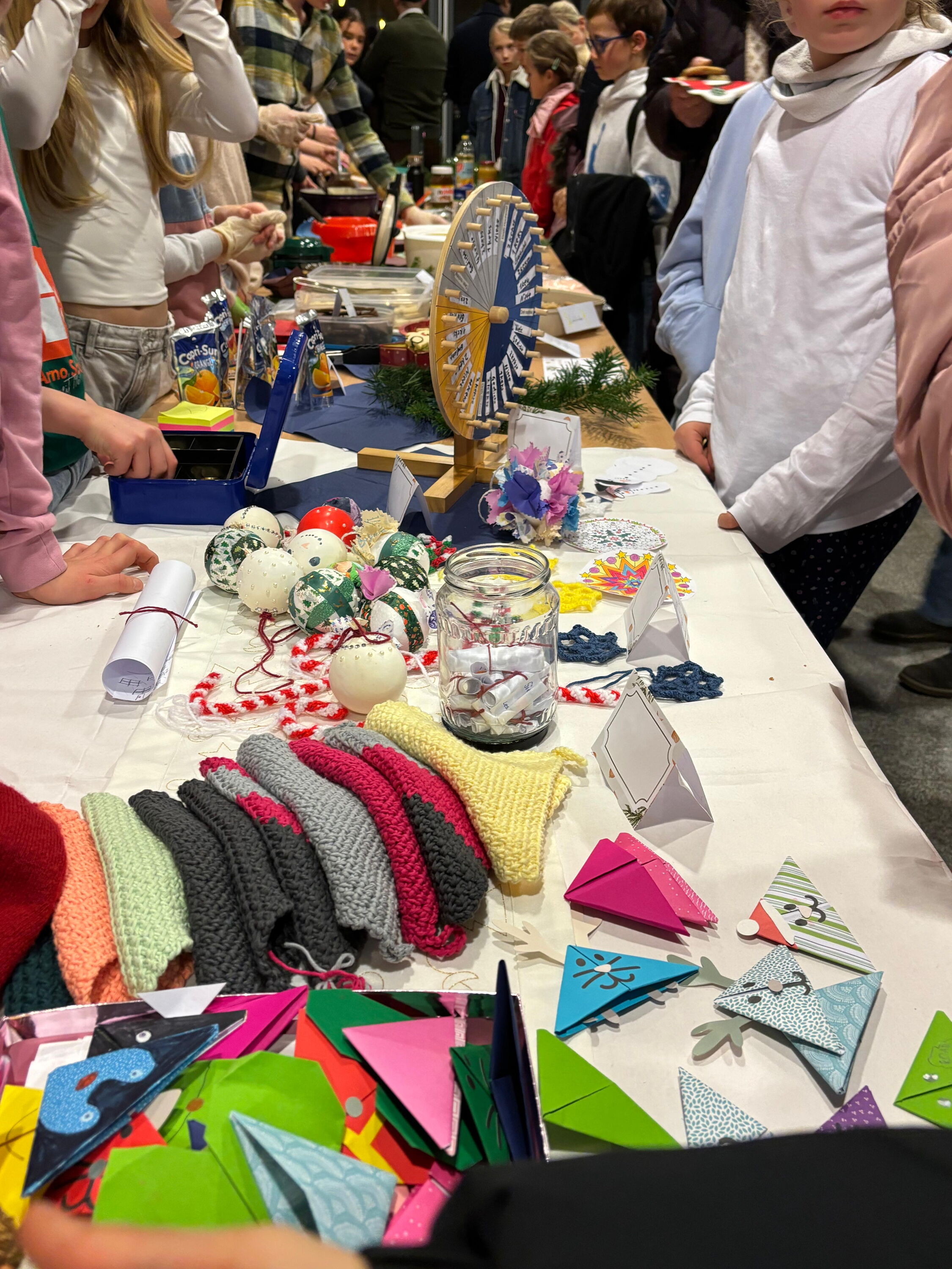 Kinder umringen den Stand mit verschieden Sachen zum Verkaufen und einem Glücksrad