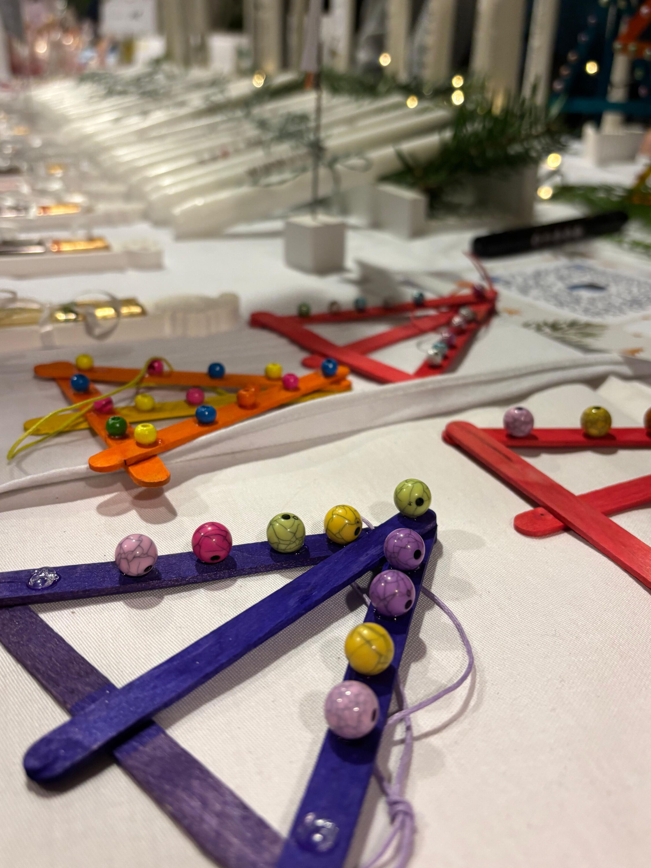 bunte Weihnachtsbaumanhänger aus Holzstäben mit bunten Kugeln dekoriert