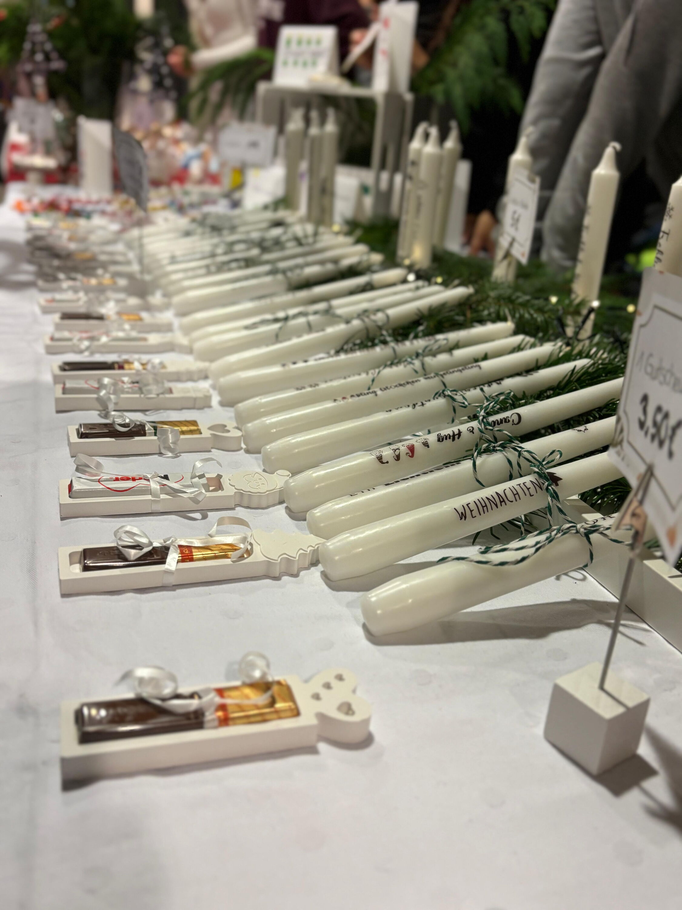 weiße Weihnachtskerzen mit Sprüchen und Zweigen dekoriert